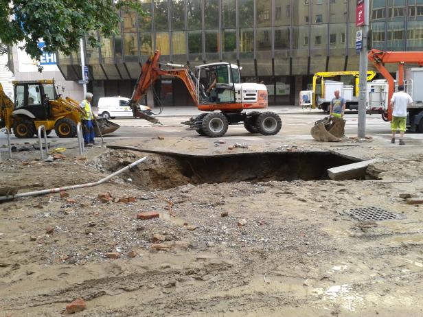 Bauarbeiten in einer städtischen Umgebung mit Baggern und Bauarbeitern.