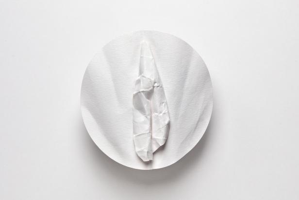 Ein zerknülltes Stück Papier liegt auf einem runden Papierfilter.