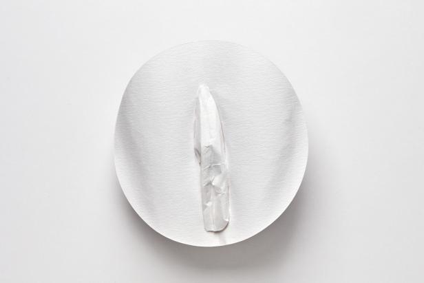 Ein weißes, zerknittertes Objekt liegt auf einer weißen, runden Oberfläche.
