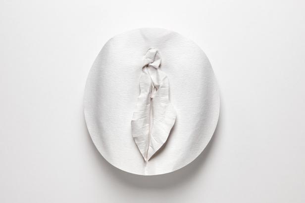 Eine Vulva-Skulptur aus weißem Papier auf einem weißen Hintergrund.