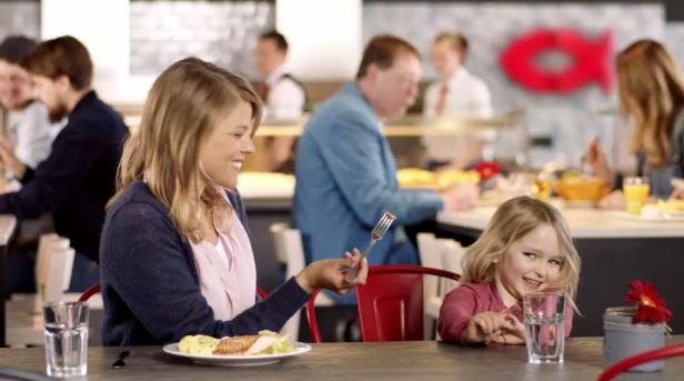 Nordsee - Wir sind Fisch - TV-Spot - Bild 2 - Jung von Matt Eine Frau hält eine Gabel mit Essen, während ein kleines Mädchen daneben sitzt und lächelt.
