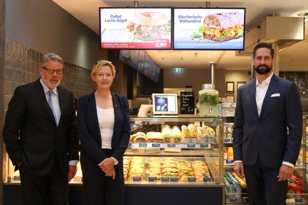 Kamps Heiner (Gesellschafter), Seggewiß Hiltrud (GF), Jung Robert (GF) - Nordsee Deutschland Drei Personen stehen vor einer Theke mit belegten Brötchen und Wraps in einem Geschäft.