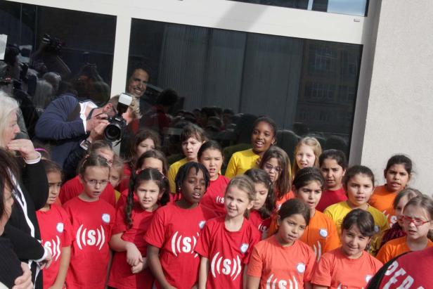 Eine Gruppe von Kindern steht vor einem Gebäude und trägt T-Shirts mit einem Logo.