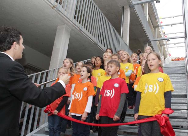 Eine Gruppe Kinder steht auf einer Treppe und singt bei einer Veranstaltung.