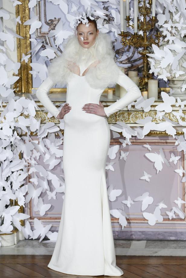 Eine Frau in einem weißen Kleid mit Schmetterlingen im Hintergrund.