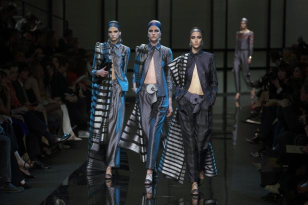 Drei Models präsentieren schwarz-weiß gemusterte Ensembles auf einem Laufsteg.