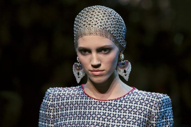 Eine Frau mit einem mit Schmucksteinen besetzten Haarnetz und großen Ohrringen.