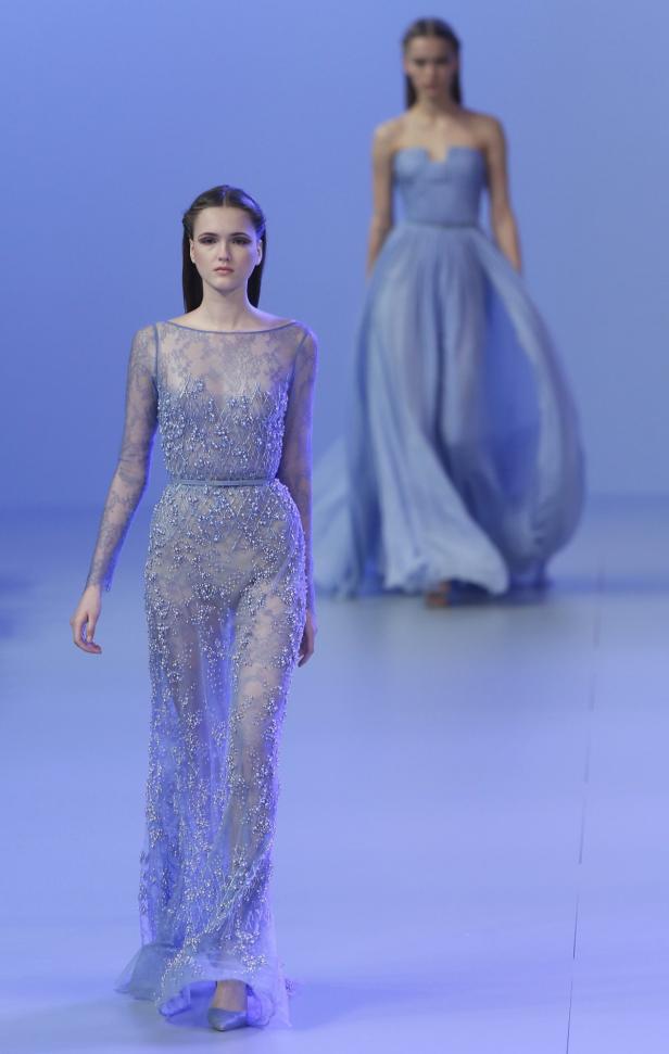 Zwei Models präsentieren blaue, bodenlange Abendkleider auf einem Laufsteg.