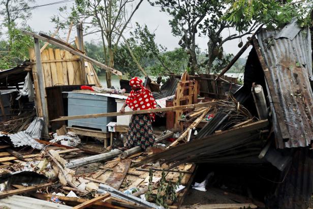 A woman clears her house that was demolished by the cyclone Amphan in Satkhira