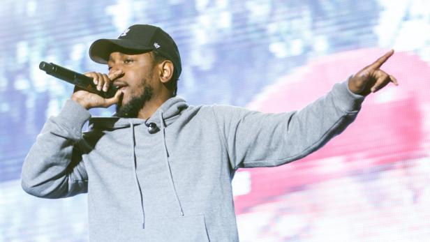 Kendrick Lamar rappt mit einem Mikrofon in der Hand und zeigt mit dem Finger.