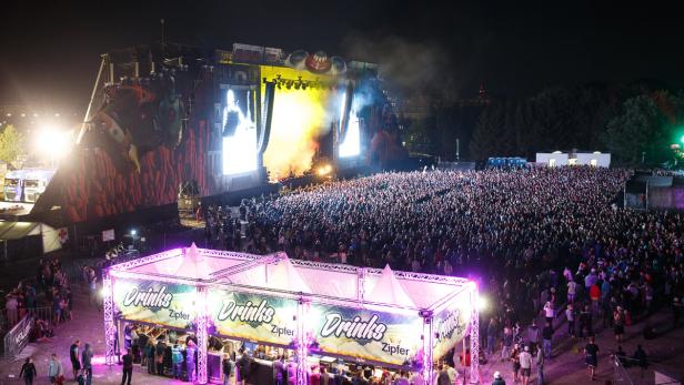 Eine große Menschenmenge versammelt sich vor einer Bühne bei einem Open-Air-Konzert bei Nacht.