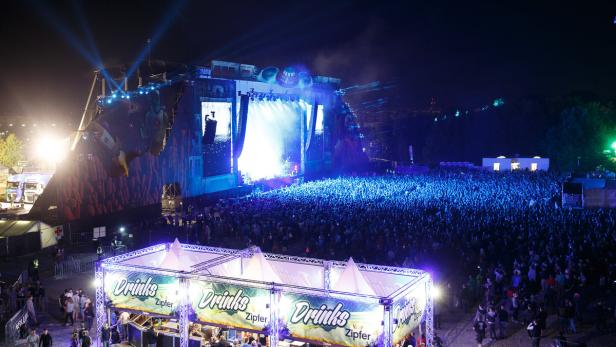 Eine große Menschenmenge versammelt sich vor einer Bühne bei einem Open-Air-Konzert bei Nacht.