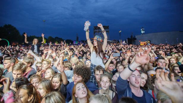 Eine große Menschenmenge jubelt bei einem Open-Air-Konzert.