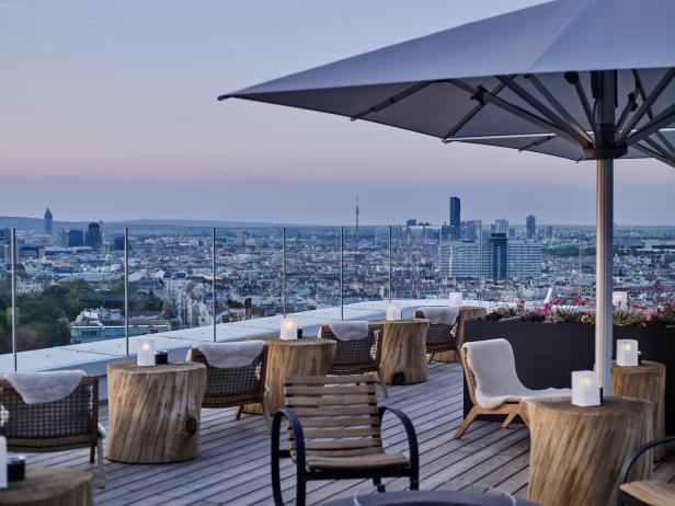 Eine Dachterrasse mit Blick auf Wien bei Dämmerung.