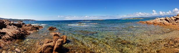 Panoramablick auf eine felsige Küste mit klarem, türkisfarbenem Wasser.