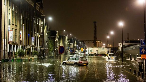 Ein überschwemmte Straße in der Nacht mit einem Auto im Wasser.