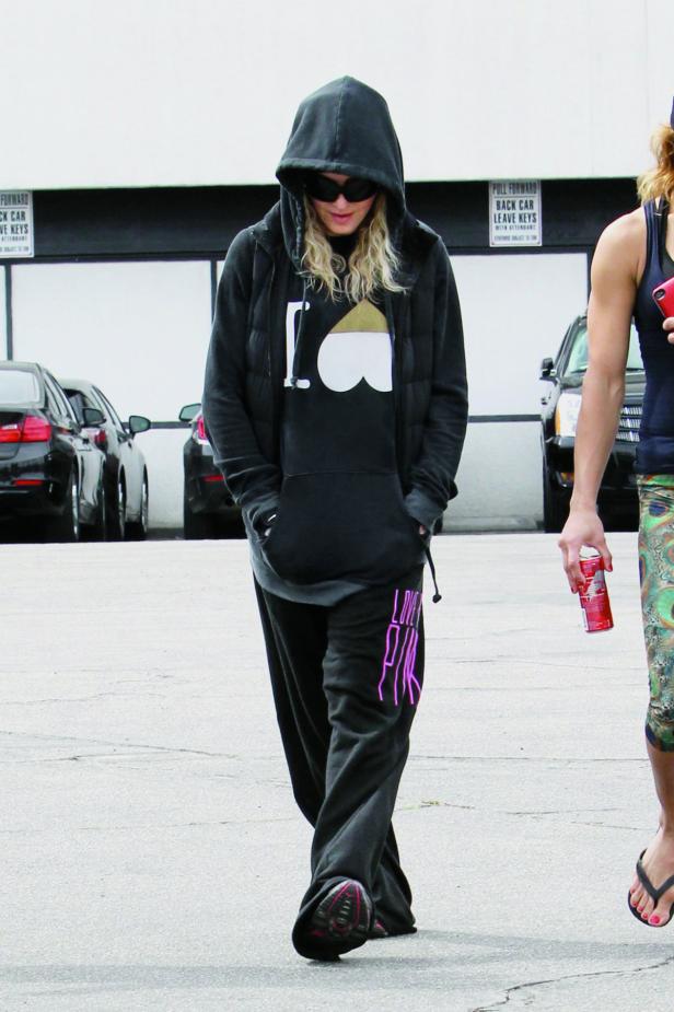 Madonna in Trainingskleidung und Sonnenbrille geht auf einem Parkplatz entlang.