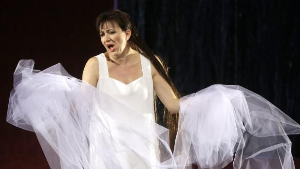 Eine Frau in einem weißen Kleid singt auf einer Bühne.