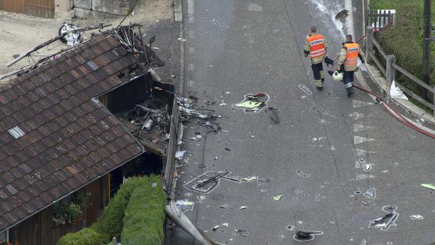 Nach einem Flugzeugabsturz gehen Feuerwehrleute eine mit Trümmern übersäte Straße entlang.