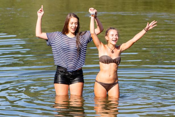 Zwei junge Frauen stehen im Wasser und lachen.