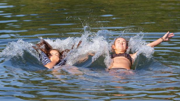 Zwei junge Frauen planschen im Wasser und spritzen mit den Händen.