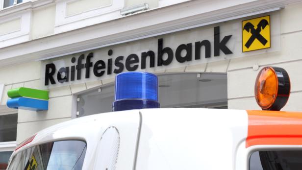 Ein Einsatzfahrzeug steht vor einer Raiffeisenbank.