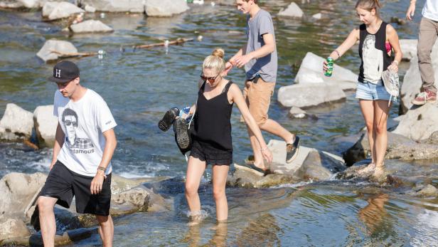 Eine Gruppe von Menschen watet durch einen Fluss.