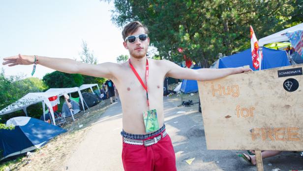 Ein Mann mit Sonnenbrille bietet auf einem Festival kostenlose Umarmungen an.