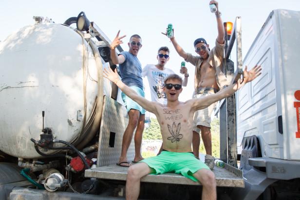 Eine Gruppe junger Männer feiert auf der Ladefläche eines Lastwagens mit Bierdosen.