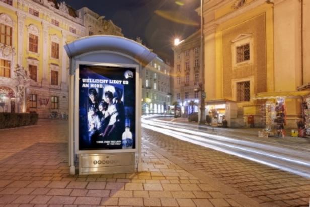 Eine Bushaltestelle mit einer Werbung für Wodka in einer nächtlichen Stadtlandschaft.