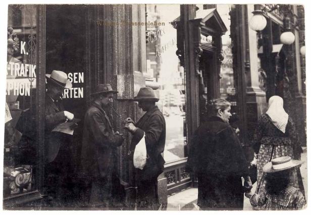 Eine historische Aufnahme von Menschen vor Geschäften in einer belebten Straße.