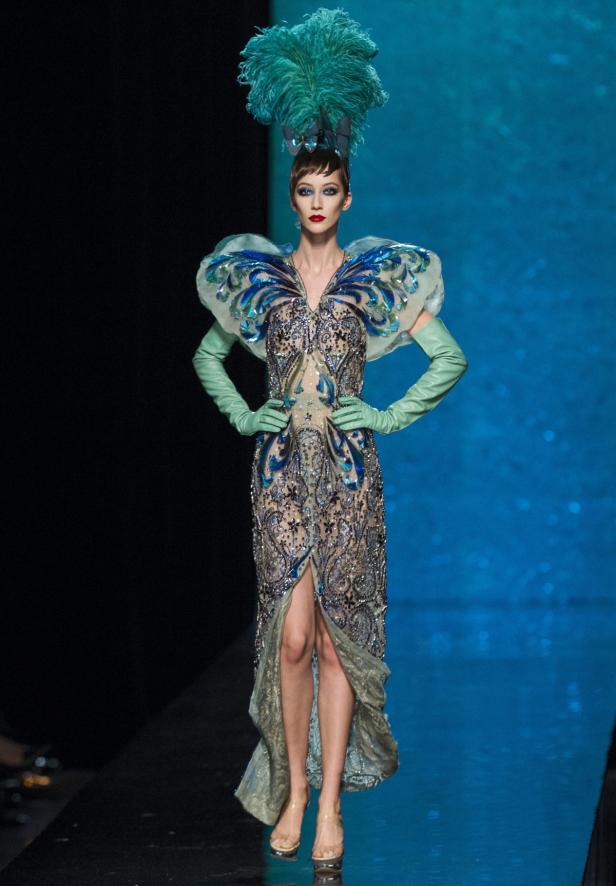 Gaultier-Model: Höchste Schneiderkunst mit pfauenartiger Anmut Eine Frau in einem aufwendigen Kleid mit Federschmuck auf einem Laufsteg.