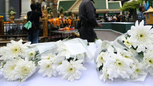 Blumen vor Anschlagsort Mehrere Sträuße weißer Chrysanthemen liegen auf einem Tisch.