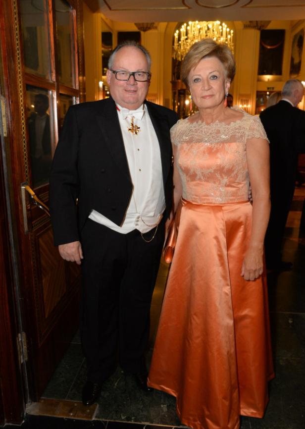 Ein Mann im Frack mit einer Ordensdekoration und eine Frau in einem apricotfarbenen Abendkleid posieren für ein Foto.