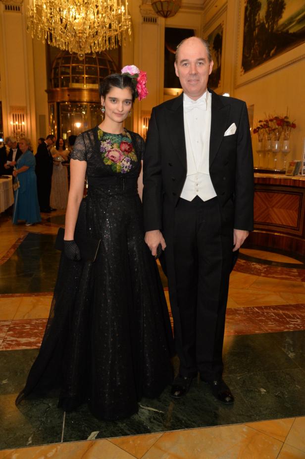 Eine Frau in einem schwarzen Kleid mit Blumenmuster und ein Mann im Smoking posieren für ein Foto.