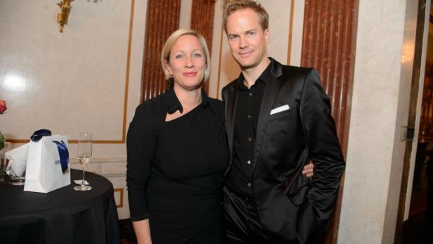 Eine Frau in einem schwarzen Kleid und ein Mann in einem schwarzen Anzug posieren für ein Foto.