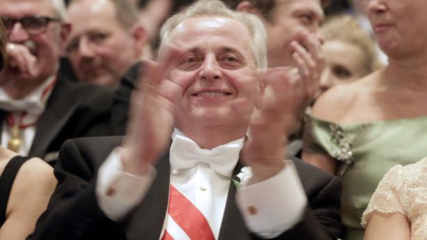 Ein Mann im Anzug klatscht in die Hände, umgeben von anderen Personen.