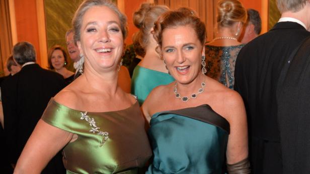 Zwei Frauen in Abendkleidern lächeln auf einer Veranstaltung.