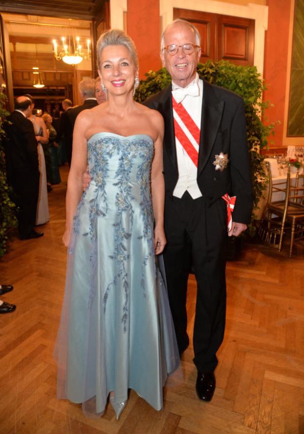 Eine elegant gekleidete Frau und ein Mann im Smoking posieren für ein Foto.