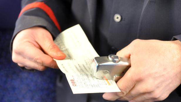 Ein Zugbegleiter entwertet eine ÖBB-Fahrkarte.