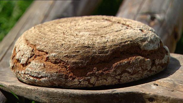 Ein Laib Brot liegt auf einem Holzbrett.