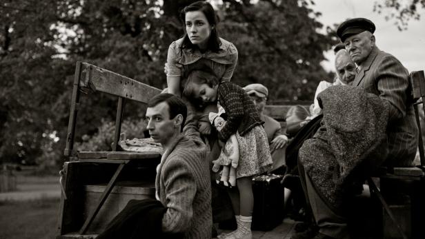 Eine Gruppe von Menschen sitzt auf der Ladefläche eines Lastwagens.