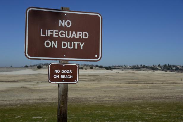 Ein Schild warnt: „Kein Rettungsschwimmer im Dienst“ und „Keine Hunde am Strand“.