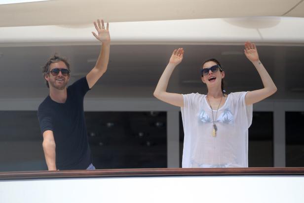 Anne Hathaway und ihr Mann winken von einer Yacht.