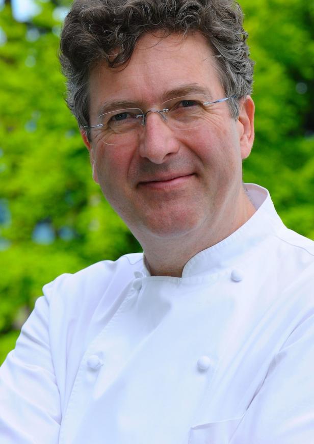 Ein Mann mit Brille und Kochjacke lächelt in die Kamera.