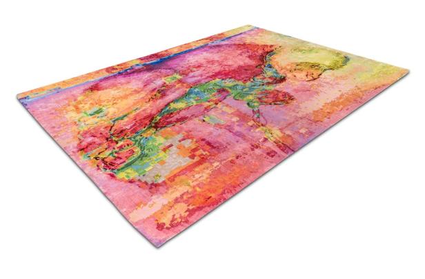 Ein abstrakt gemusterter Teppich in Rosa-, Orange- und Grüntönen liegt auf einem weißen Untergrund.