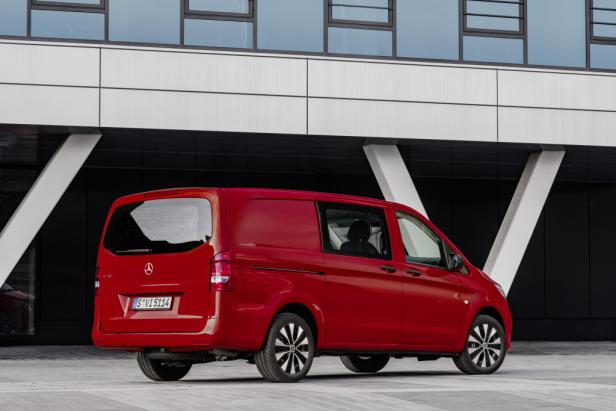 Ein roter Mercedes-Benz Vito Kastenwagen steht vor einem modernen Gebäude.