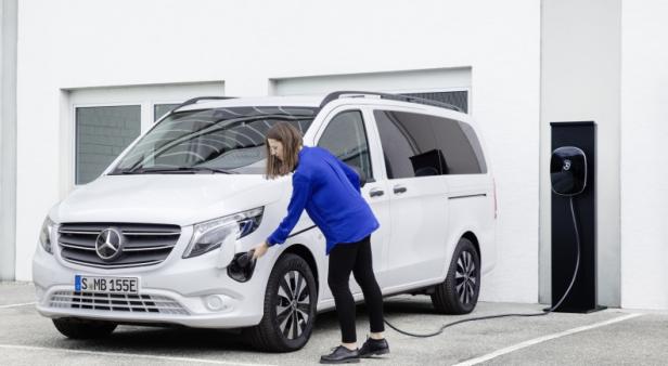 Eine Frau schließt einen weißen Mercedes-Benz eVito an eine Ladestation an.