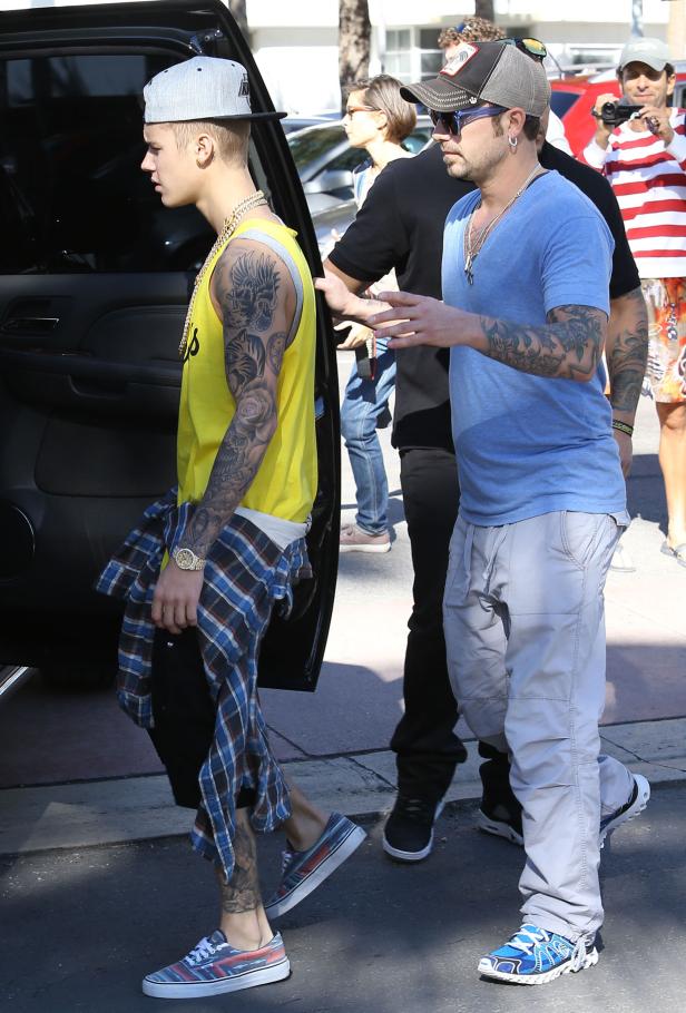 Justin Bieber verlässt ein Gebäude, begleitet von einem Mann mit Tätowierungen.