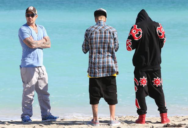 Drei Personen stehen am Strand vor dem türkisfarbenen Meer.